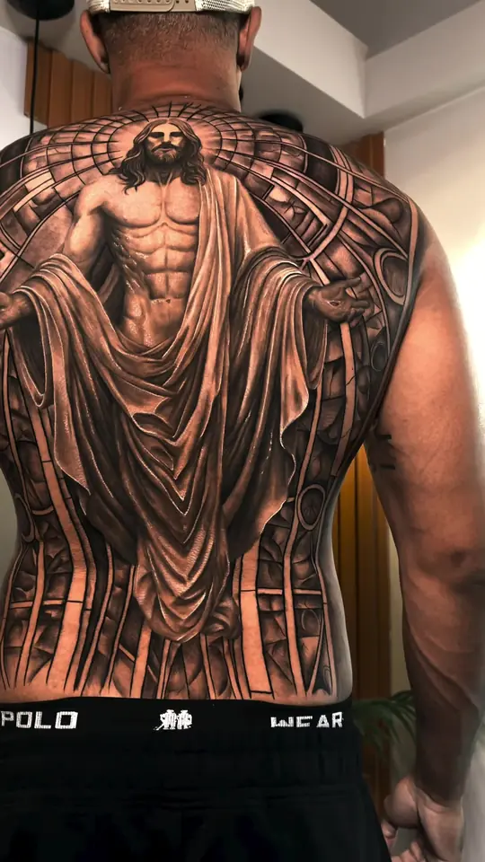 O fechamento de costas pronto: Jesus de braços abertos diante de um vitral.
